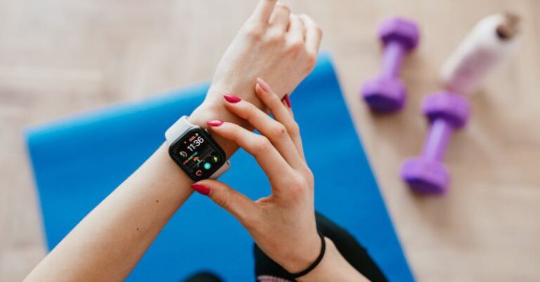 Tracker - Anonymous sportswoman checking smart watch and sitting on mat