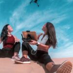 Gadgets - Two Woman Sitting On Sand While Playing Drone